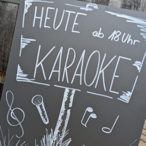 Tafel mit der Aufschrift: Heute ab 18 Uhr Karaoke.