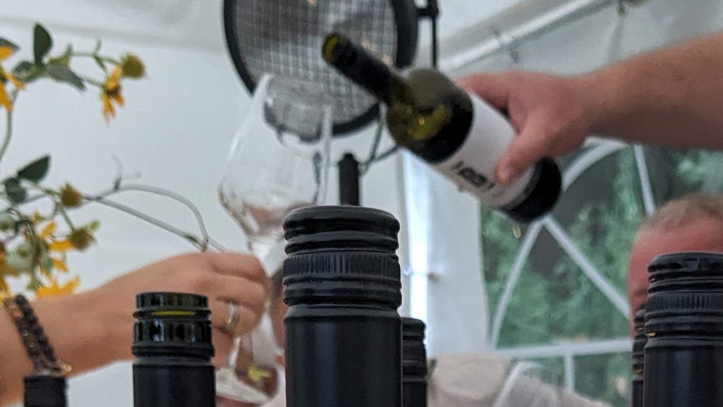 Jemand hält ein Weinglas in der Hand, in das Wein vom Weingut Buchert eingeschenkt wird.